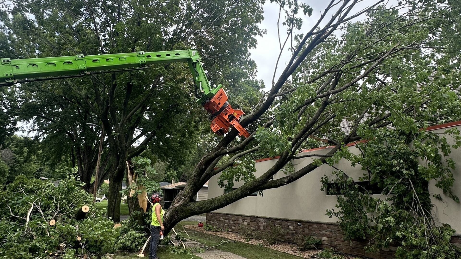 Storm damaged tree being picked off roof of Baaken Young in River Falls, WI