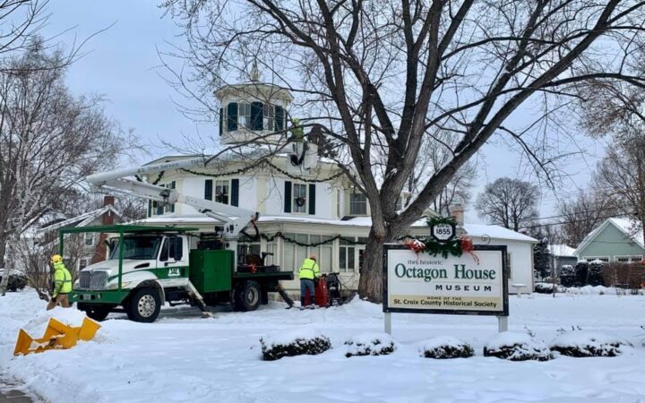 People trimming a tree at the Octagon House in Hudson, WI