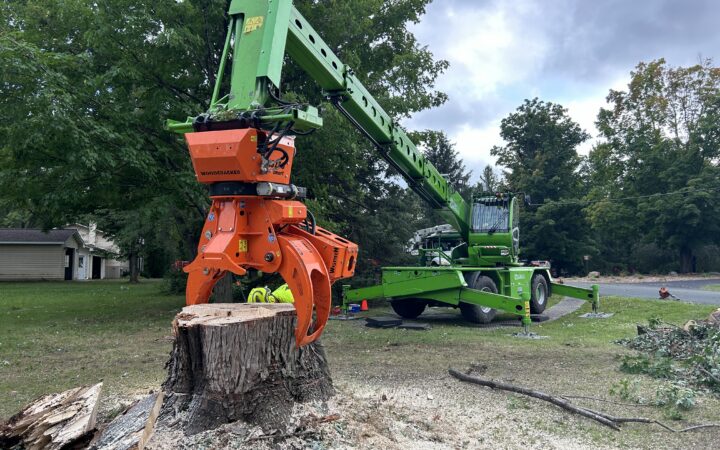 Merlo grapple picking up a silver maple trunk