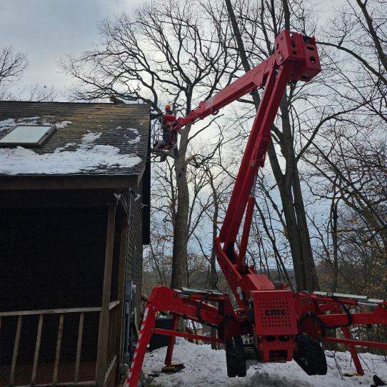 Person in spider lift pruning an oak tree in winter on Somers Landing Road in North Hudson, WI