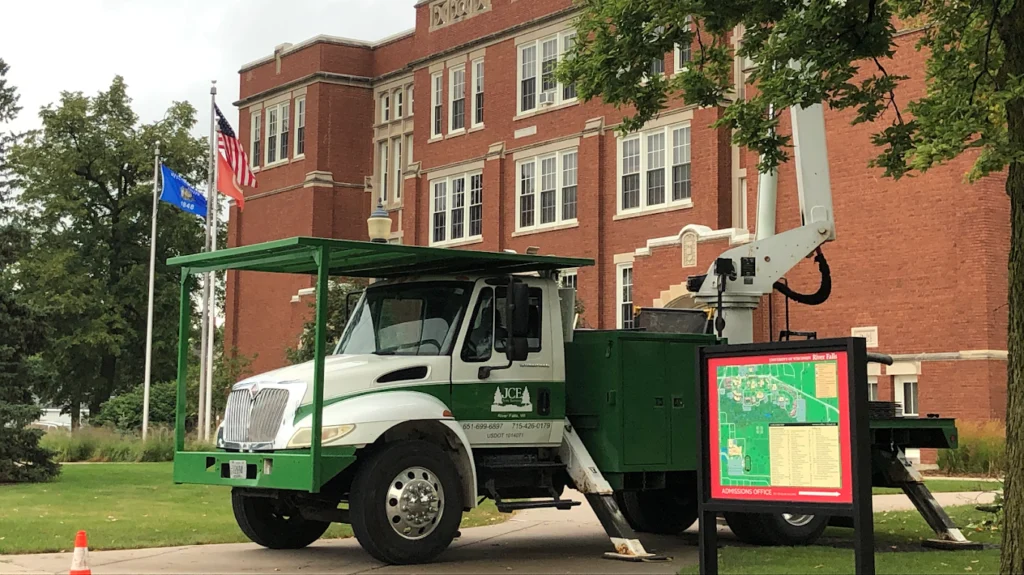 Green and white bucket truck outside a building at UWRF