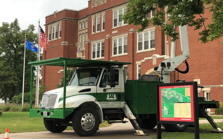 Green and white bucket truck outside a building at UWRF